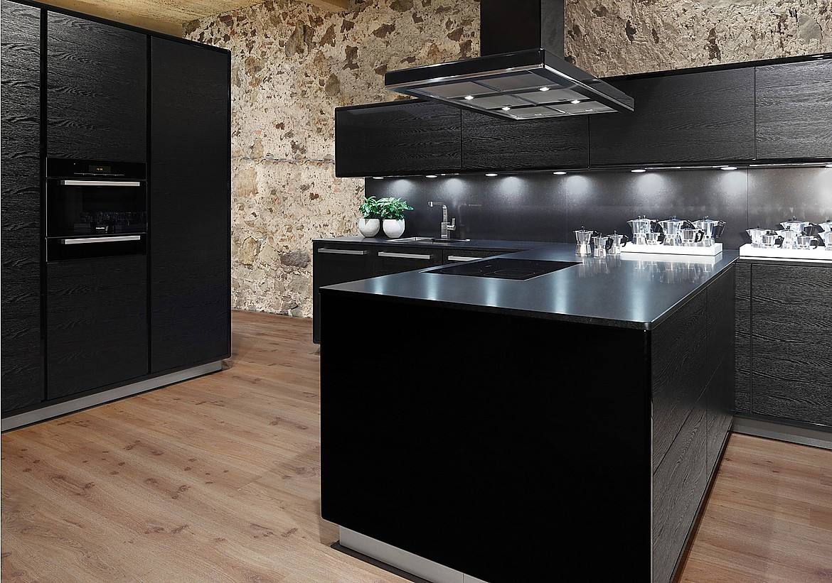 NATURA cocina chapada en madera lacada en negro. Los armarios columna Modern ART Verticon y los armarios altos ART TIP-TEC equipados con el sistema mecánico de apertura de puertas Sensomatic destacan junto a la encimera „stoneline“ Granit Nero satinado. Zuordnung: Stil Cocinas de diseño, Planungsart Cocinas americanas (abiertas)