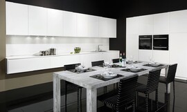 Cocina blanca de puertas sin tiradores de elegantes líneas de diseño. Los tiradores han sido sustituidos por elegantes acanaladuras. Junto a la perfección del color blanco destaca la encimera de Glasline, de vidrio esmaltado de color negro. Los paneles correderos redondean la perfección de cajones y puertas de esta cocina con isla. Zuordnung: Stil Cocinas de diseño, Planungsart Cocinas en L