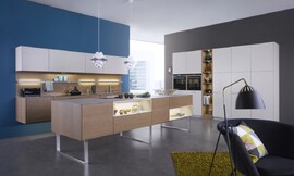 Cocina de arquitectura abierta, transmite a todo su hogar la elegancia de las líneas puras de sus muebles, que colgados en la pared o apoyados en elegantes patas de diseño, dan una sensación de ligereza casi etérea. La mezcla de colores y texturas, el roble cobrizo de los muebles bajos y el lacado Sahara de los muebles altos, crean un contraste de color en la sala, que subraya su elegancia natural. [[more]] Una elegante y delicada encimera de cerámica realza el carácter natural. Las baldas luminosas y los elementos de iluminación repartidos por la cocina destacan los detalles y relajan las formas, permitiéndole dar a su cocina el toque personal que se merece. La instalación de la campana extractora Plasma Norm, completamente integrada en los muebles y extremadamente silenciosa, le invita a integrar esta elegante cocina en su sala de estar. Zuordnung: Stil Cocinas de diseño, Planungsart Detalles del diseño