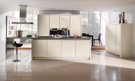 Moderno, luminoso y agradable: En los frentes lacados sin tirador de esa cocina en isla, la luz se refleja de manera especialmente atractiva. El confortable bar invita a sentarse y relajarse. Zuordnung: Stil Cocinas de diseño, Planungsart Cocinas en línea