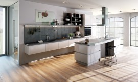 Exclusiva cocina de diseño “suspendida”. Los relucientes frentes blancos con diseño sin tirador, remarcan la ligereza del diseño adicionalmente. Numerosos detalles como la estantería encima de la zona del lavabo y la barra con óptica de piedra redondean la imagen global de la cocina. Zuordnung: Stil Cocinas de diseño, Planungsart Cocinas con isla