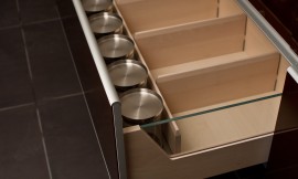 Equipamiento interior de cajones con elementos de cristal y en madera de haya con baldas de distribución extraíbles y esquinas redondeadas que facilitan la limpieza. Los frentes del cajón tienen cantos de aluminio. Zuordnung: Stil Cocinas modernas, Planungsart Cocinas en L