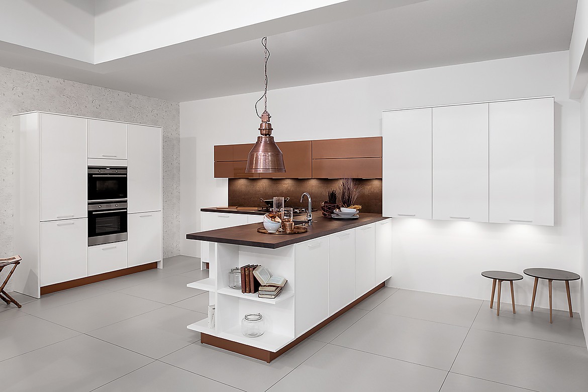 Le apetece un poco más de lujo? Cualquiera que busque una cocina de alta calidad con un diseño muy elegante, puede dejarse inspirar por esta cocina abierta. Snow es el nombre apropiado del tono de color de este frente, con un acabado mate. El diseño se completa con elementos de vidrio esmerilado de color cobre. Zuordnung: Stil Cocinas de diseño, Planungsart Cocinas en L