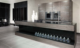 Una combinación exclusiva de materiales: la encimera de acero fundido sobre madera cepillada en combinación con los frentes de cristal negro brillante hacen de esta isla de cocina un objeto de arte. Zuordnung: Stil Cocinas modernas, Planungsart Cocinas americanas (abiertas)