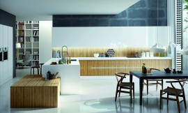 Cocina amplia, familiar, con encimera de cuarzo blanco, muebles altos de frentes en blanco, muebles bajos con frentes estratificados, imitación madera y sin tiradores. Los armarios columna, también en blanco, con los electrodomésticos incrustados ofrecen además un espacio de almacenaje extra, muy útil. El diseño integra en el mismo espacio la cocina y la sala de estar para crear un lugar cómodo y amplio con una distribución lógica y ergonómica. Un diseño que garantiza la superficie necesaria para organizar las diferentes zonas de trabajo y sala de estar y así poder disfrutar de la cocina en compañía de toda la familia. Zuordnung: Stil Cocinas modernas, Planungsart Cocinas en U