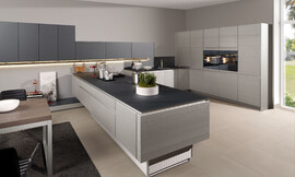 Esta cocina abierta pensada para espacios amplios nos ofrece mucho más que la funcionalidad de un diseño racional. Los muebles son de estructura de madera, lacados en metal y combinados con frentes de cristal mate. La mezcla de materiales como la madera cepillada, el lacado metálico y el cristal le dan un toque muy extravagante a la cocina. Sin embargo, la protagonista de esta cocina es la isla, completamente regulable en altura. Zuordnung: Stil Cocinas modernas, Planungsart Cocinas con isla