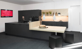 En esta cocina con isla con armarios suspendidos parcialmente Rotpunkt demuestra la más alta experiencia en el diseño. Gracias al diseño de los frentes en Carbon oscuro con una superficie mate, estamos ante un clásico-moderno y, por otra parte, la belleza extraordinariamente noble. Por supuesto, lo que llama la atención aquí es la gran mesa cuadrada. Zuordnung: Stil Cocinas de diseño, Planungsart Cocinas en línea