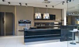 Esta isla de diseño muy moderno con barra y con armarios columna donde están integrados los electrodomésticos. El diseño se une a la funcionalidad en esta cocina abierta en la que el color negro de los frentes de alto brillo le da un carácter muy elegante. Zuordnung: Stil Cocinas modernas, Planungsart Equipamiento interior de la cocina