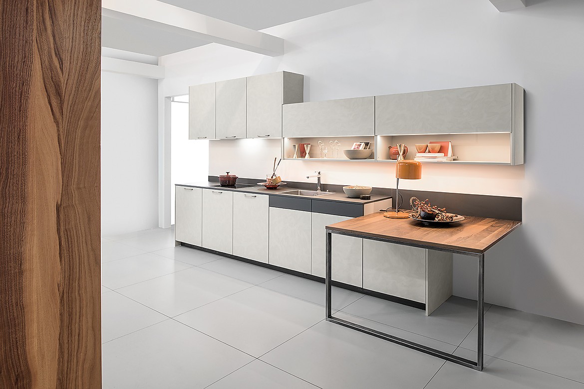 Cocina exclusiva con el frente en óptica de hormigón y mesa de extensión práctica con una superficie de alta calidad en chapa de nogal. Zuordnung: Stil Cocinas de diseño, Planungsart Cocinas en línea