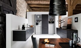 Los armarios de roble negro dan el toque de elegancia a esta estancia donde la arquitectura permite pasar de una cocina funcional a una acogedora sala de estar gracias a los armarios colgantes y los tonos oscuros de la madera de robles. Zuordnung: Stil Cocinas modernas, Planungsart Equipamiento interior de la cocina
