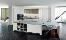 Diseño de cocina refinado: La zona del lavabo y los armarios blancos se alejan visualmente y se funden con la pared. La gran isla con frentes si tirador,  puntua con sus detalles prácticos tales como la estantería abierta y la mesa. Zuordnung: Stil Cocinas de diseño, Planungsart Cocinas en U