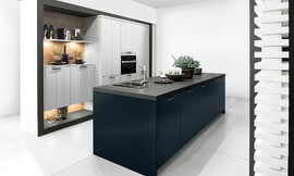 Como la noche y el día, y sin embargo, lleno de armonía: la cocina con isla en Midnight Blue ofrece un atractivo contraste con los frentes claros en Daylight Grey . En esta cocina de diseño se funde la belleza clásica y la modernidad en un todo armonioso. Los frentes con textura ondulada son muy agradables a la vista, por eso también son adecuados para cocinas rústicas. Zuordnung: Stil Cocinas de diseño, Planungsart Cocinas con isla