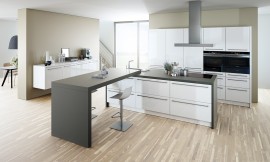 Clásico en blanco y negro: La isla esta lacada en blanco y está enmarcada por una encimera oscura que sigue en los laterales con los costados. En un ángulo de 90 °, la cocina se ha ampliado con una práctica mesa supletoria. Zuordnung: Stil Cocinas de diseño, Planungsart Cocinas con isla