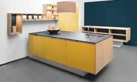 La cara soleada de esta cocina “suspendida” con isla inmediato genera buen humor. A juego el frente con el nombre &quot;Sunny&quot;. El cálido resplandor en color amarillo mate en perfecta armonía con los costados y los estantes modernos de madera clara. El diseño se complementa con un amarillo cálido llamado &quot;Grain&quot;. Zuordnung: Stil Cocinas de diseño, Planungsart Cocinas en U