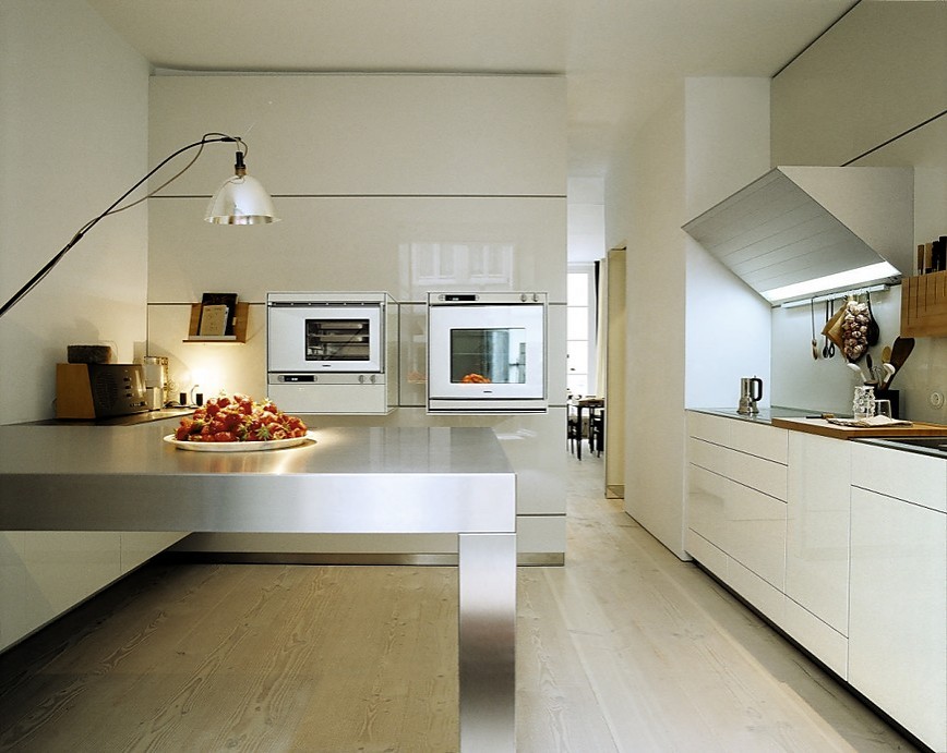 Cocina en crema de alto brillo con los electrodomésticos incrustados en armarios columnas que llegan hasta el techo (Bulthaup)