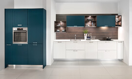 Cocina en línea con frentes de marco en laca mate en los colores blanco y Deep Blue. Una ligerea particular la obtiene la cocina gracias a su diseño “flotante”, sin zócalo. El entrepaño en acabado madera oscura crea un acogedor acento y gracias a los estantes iluminados la vajilla y los accesorios se presentan de manera óptima Zuordnung: Stil Cocinas de diseño, Planungsart Cocinas en línea