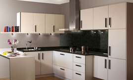 Cocina en L con barra a modo de mesa que permite crear más espacio en esta cocina. La encimera y el entrepaño oscuros hacen destacar la elegancia de los armarios blancos con tiradores de metal. Los armarios se han adaptado a las necesidades y las características del espacio disponible, con diferentes anchos de fondo de armario y encimera. Zuordnung: Stil Cocinas clásicas, Planungsart Detalles del diseño