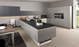 Esta cocina abierta pensada para espacios amplios nos ofrece mucho más que la funcionalidad de un diseño racional. Los muebles son de estructura de madera, lacados en metal y combinados con frentes de cristal mate. La mezcla de materiales como la madera cepillada, el lacado metálico y el cristal le dan un toque muy extravagante a la cocina. Sin embargo, la protagonista de esta cocina es la isla, completamente regulable en altura. Zuordnung: Stil Cocinas modernas, Planungsart Cocinas con isla