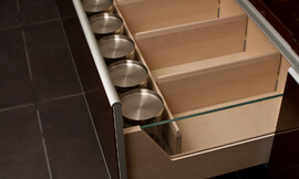 Equipamiento interior de cajones con elementos de cristal y en madera de haya con baldas de distribución extraíbles y esquinas redondeadas que facilitan la limpieza. Los frentes del cajón tienen cantos de aluminio. Zuordnung: Stil Cocinas modernas, Planungsart Equipamiento interior de la cocina