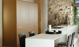 Armarios bajos con frentes sintéticos en blanco. Armarios altos lacados en laca diamante en dorado. El armario de la pared oculta detrás de dos puertas correderas los electrodomésticos. Zuordnung: Stil Cocinas de diseño, Planungsart Cocinas con office