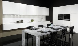 Cocina blanca de puertas sin tiradores de elegantes líneas de diseño. Los tiradores han sido sustituidos por elegantes acanaladuras. Junto a la perfección del color blanco destaca la encimera de Glasline, de vidrio esmaltado de color negro. Los paneles correderos redondean la perfección de cajones y puertas de esta cocina con isla. Zuordnung: Stil Cocinas de diseño, Planungsart Cocinas en L