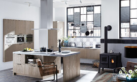 Esta cocina con isla y barra en Oak Line es un símbolo del confort. El frente de madera de roble claro en colores pastel Grey envuelve la habitación inmediatamente con calidez y confort. Zuordnung: Stil Cocinas de diseño, Planungsart Detalles del diseño