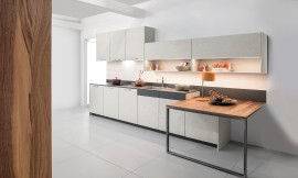 Cocina exclusiva con el frente en óptica de hormigón y mesa de extensión práctica con una superficie de alta calidad en chapa de nogal. Zuordnung: Stil Cocinas de diseño, Planungsart Cocinas en línea