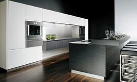 Modern ART WAVE con superficies que forman suaves ondas. El lacado de lujo brillo diamante en blanco y negro destaca junto a la encimera de acero con el fregadero integrado. Zuordnung: Stil Cocinas de diseño, Planungsart Cocinas con isla