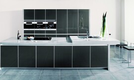Esta cocina elegante y de líneas puras en tonos metálicos con frentes de cristal y marcos metálicos. Con una isla de cocina con encimera en dos alturas no deja un detalle suelto para que pueda disfrutar de su cocina en todo momento Zuordnung: Stil Cocinas de diseño, Planungsart Cocinas con isla