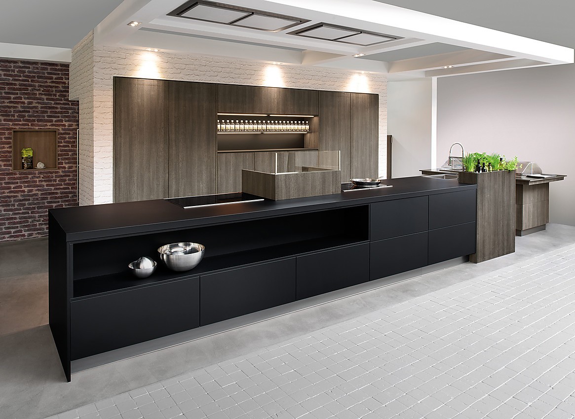 Cocina de diseño purista con los frentes sin tirador. El color negro de la isla se funde con el color de madera oscuro Late Oak de los armarios altos y crea una bonita composición. Zuordnung: Stil Cocinas de diseño, Planungsart Cocinas con isla